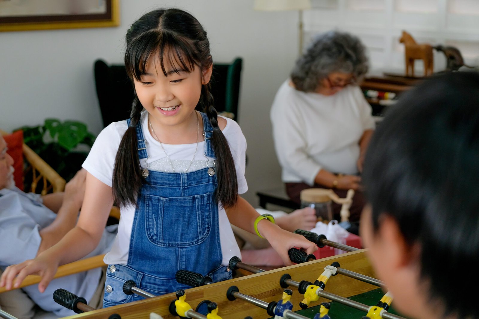 little-girl-has-fun-with-table-soccer-while-grandp-2023-11-27-05-24-29-utc